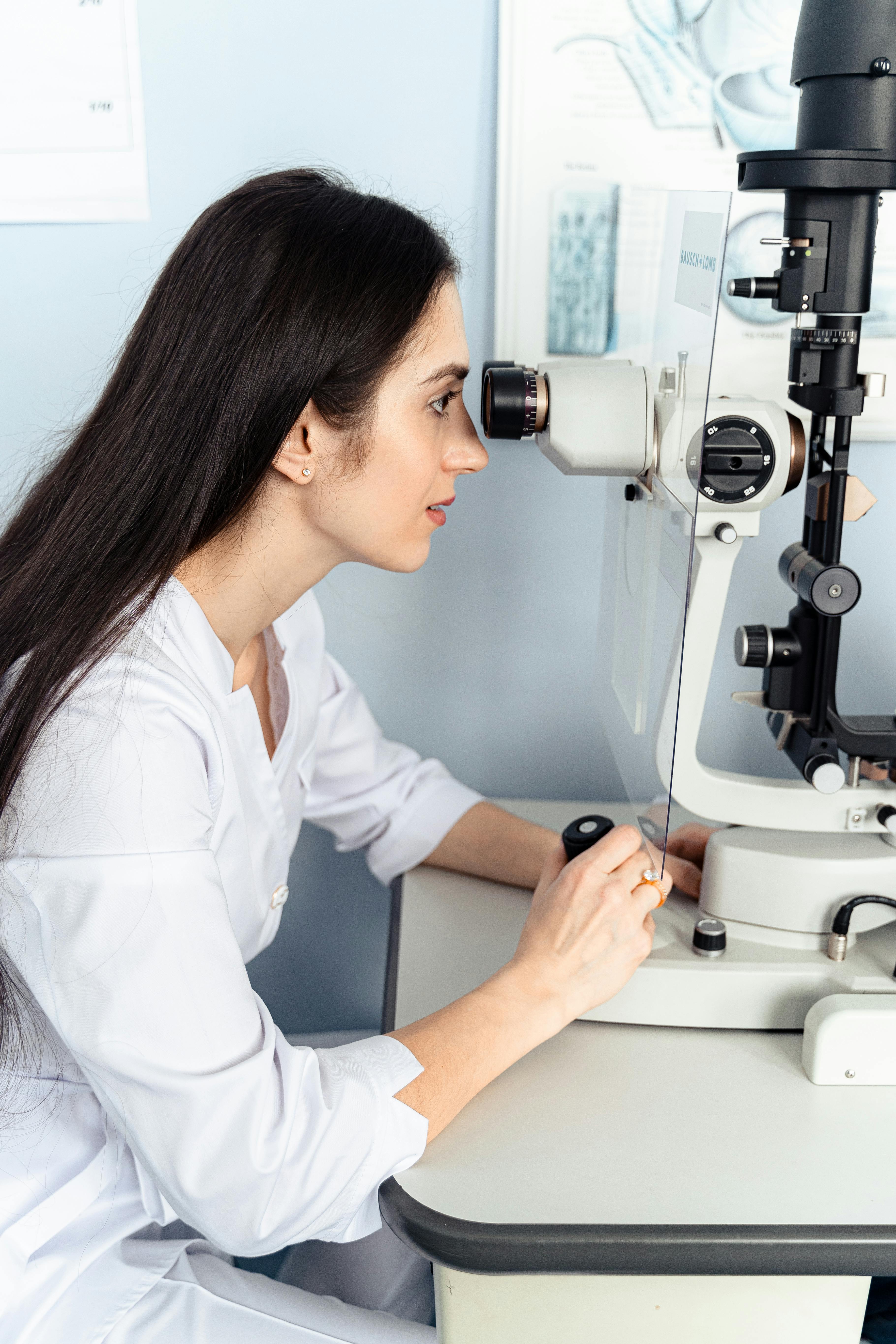 Eye care professional using slit lamp exam equipment